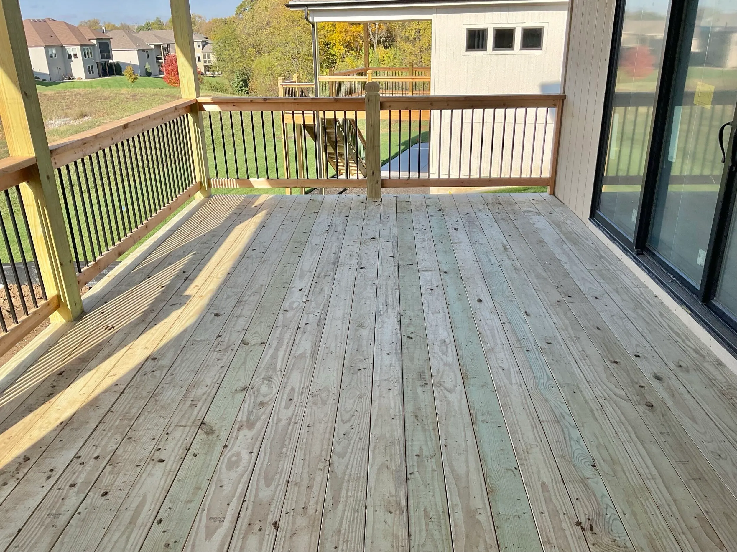 Covered wood deck with metal-baluster rail overlooking neighborhood