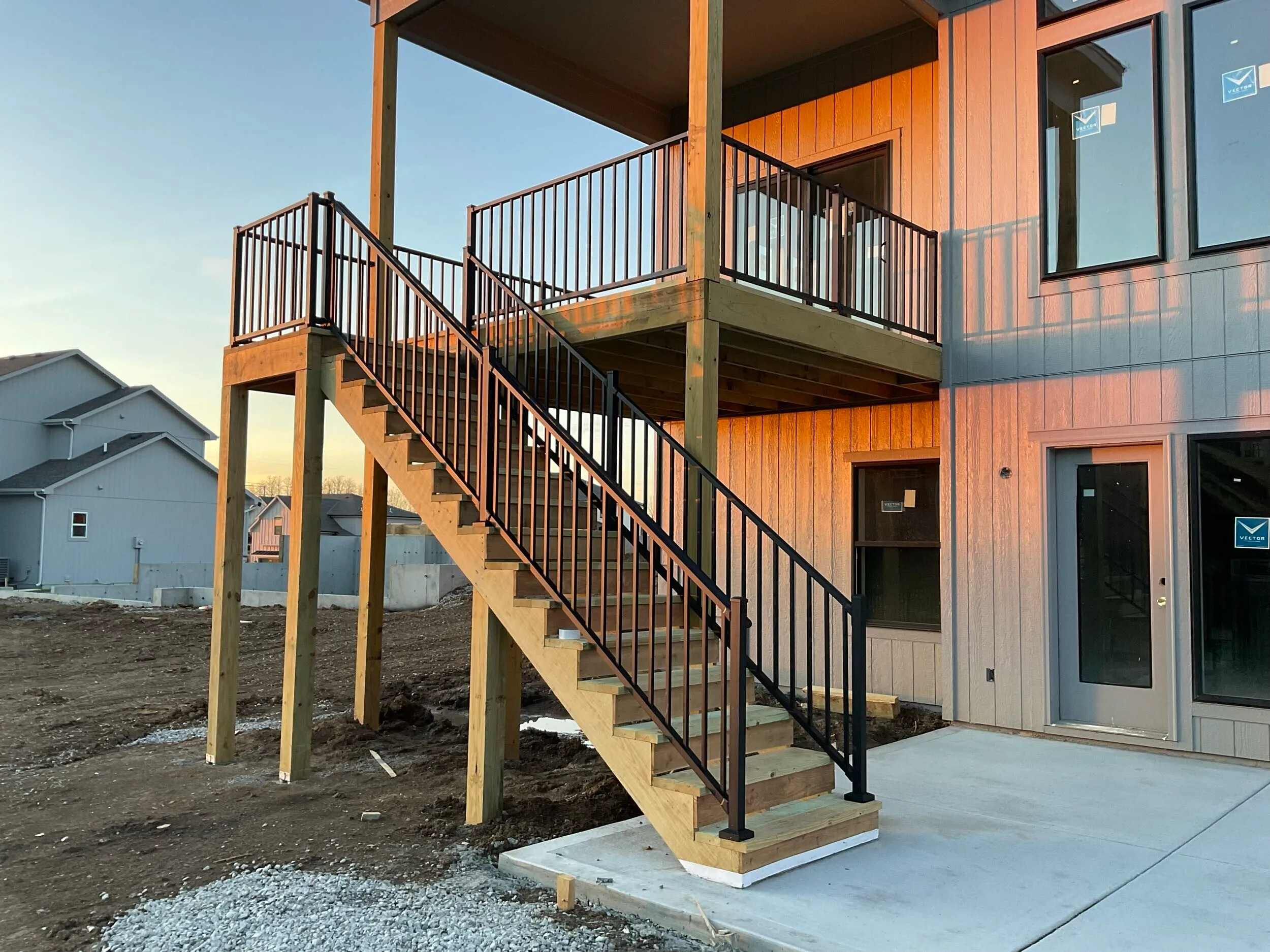 Two-story wood deck with metal-baluster railing and stairs down to grade